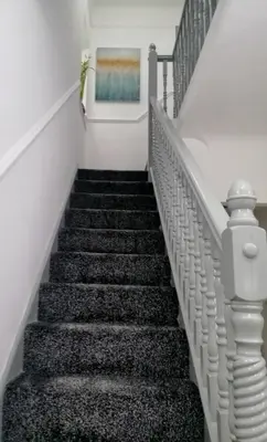 a stairway with black and white stairs and a painting at Modernised 3 Bed House in Liverpool