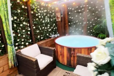 a hot tub on a patio with a chair and a table at Squirrel Hideaway with Hot Tub in Formby, Liverpool in Formby