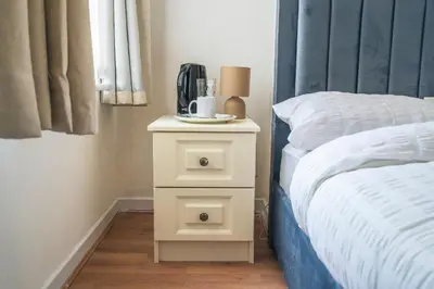 a bed with a white night stand next to a bed with a bed gmaxwell gmaxwell at Majestic House Liverpool in Liverpool