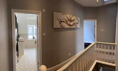 a hallway with a staircase with a painting on the wall at Four Bedroom High Spec Victorian Townhouse in Clitheroe
