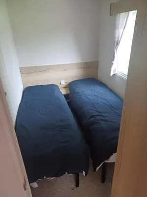 two blue beds in a room with a window at Ye Old'e Man - Sleeps 6 & Pet Friendly in Grange Over Sands