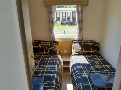 two beds in a small room with a window at Ye Old'e Man - Sleeps 6 & Pet Friendly in Grange Over Sands