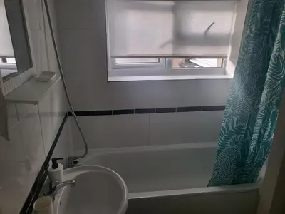 a bathroom with a sink and a tub and a window at Comfy Home in Liverpool