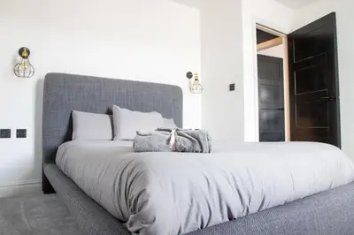 a bedroom with a large bed with a gray headboard at Gynn Stays - Apartment One in Blackpool