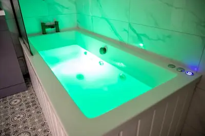 a bathroom with a tub with a sink in it at Gynn Stays - Apartment Two in Blackpool