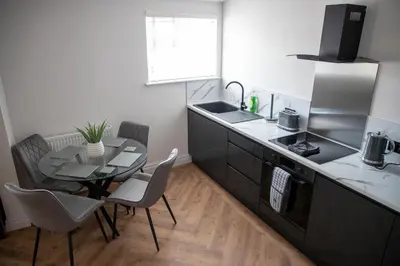 a small kitchen with a table and a sink at Gynn Stays - Apartment Two in Blackpool