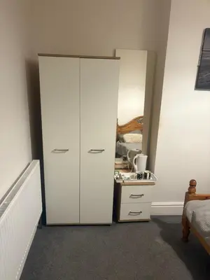 a bedroom with a white cabinet and a dresser at Fir Trees in Blackpool