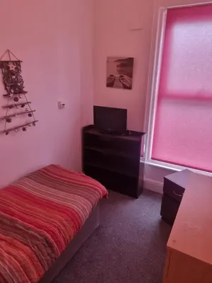 a bedroom with a bed and a tv and a window at Fir Trees in Blackpool