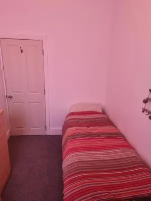 a small room with a bed with a striped blanket at Fir Trees in Blackpool