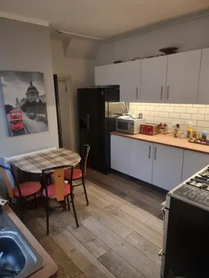 a kitchen with white cabinets and a table with chairs at Fir Trees in Blackpool