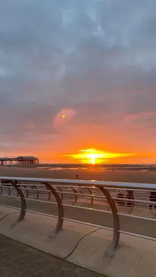 a sunset over the beach and the ocean with a bench at Double Room with Private Bathroom 16 Havelock Street - 6 in Blackpool