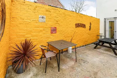 a table and chairs next to a yellow wall at Carlton Villa - Gorgeous detached home with parking in Liverpool