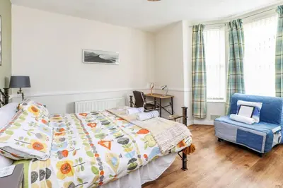 a bedroom with a bed and a blue chair at Carlton Villa - Gorgeous detached home with parking in Liverpool