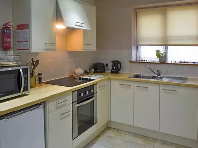 a kitchen with white cabinets and a microwave at Clougha View - 29531 in Scotforth