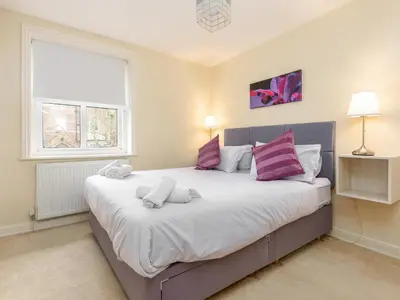 a bedroom with a large bed with purple and white pillows at Mulberry House in Lytham St Annes