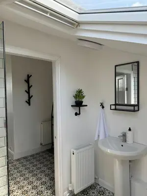 a white bathroom with a sink and a mirror at The Eaves - Victorian second floor, open plan apartment in Southport