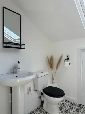 a bathroom with a sink and a toilet and a mirror at The Eaves - Victorian second floor, open plan apartment in Southport
