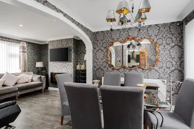 a living room with a table and chairs and a mirror at Homestay in Knowsley