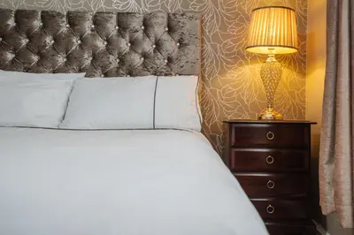 a bedroom with a bed and a lamp on a dresser at Homestay in Knowsley