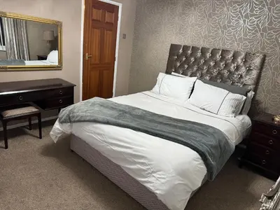 a bedroom with a large bed and a mirror at Homestay in Knowsley