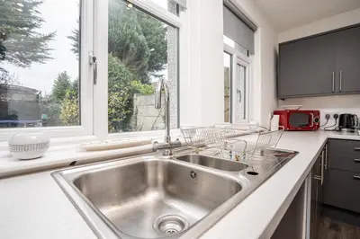 a kitchen with a stainless steel sink and a window at Homestay in Knowsley