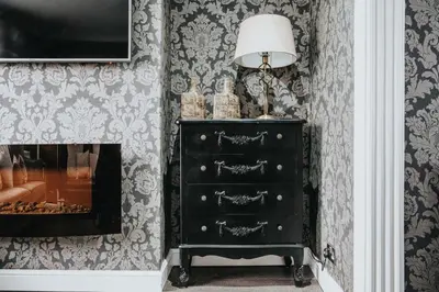 a black dresser with a lamp and a fireplace at Homestay in Knowsley