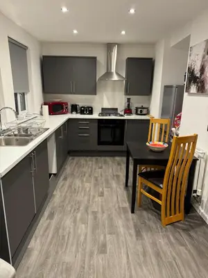 a kitchen with black cabinets and a table and chairs at Homestay in Knowsley