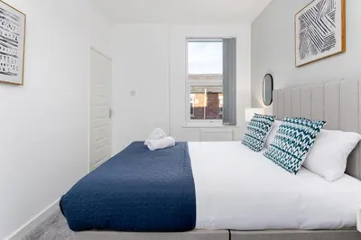 a bedroom with a large bed with blue and white pillows at Cowley House - Air Host & Stay - Sleeps 7 in Liverpool
