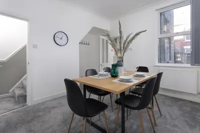 a dining room with a wooden table and black chairs at Cowley House - Air Host & Stay - Sleeps 7 in Liverpool