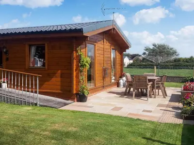 a small wooden cabin with a table and chairs at Chestnut Lodge in Pilling