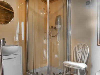 a shower with a glass door and a chair in a bathroom at Chestnut Lodge in Pilling