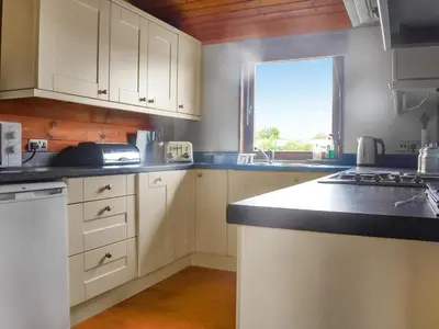 a kitchen with white cabinets and a counter top at Chestnut Lodge in Pilling