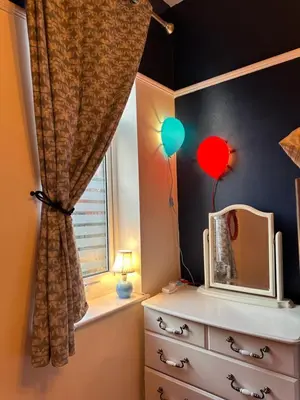 a bedroom with a window with a dresser and balloons at Circus Suite Blackpool in Blackpool