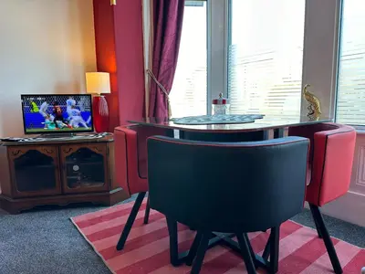 a living room with a glass table and a television at Circus Suite Blackpool in Blackpool