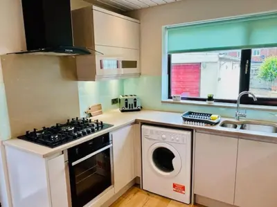 a kitchen with a stove and a washing machine at Fairholmes House in Thornton