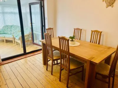 a wooden dining room table and chairs with a view of a balcony at Fairholmes House in Thornton