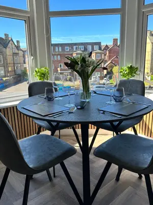 a table with chairs and a vase of flowers on it at No1,luxury 1 bed apartment in Saint Annes on the Sea