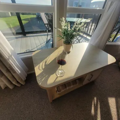 a table with a glass of wine and flowers on it at Beachside Lodge - Sleeps 6 - Pets ok - Parking in Morecambe