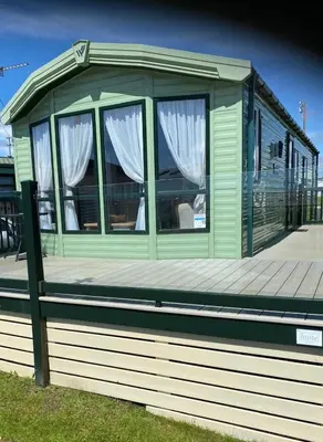 a green house with windows on a wooden deck at Beachside Lodge - Sleeps 6 - Pets ok - Parking in Morecambe
