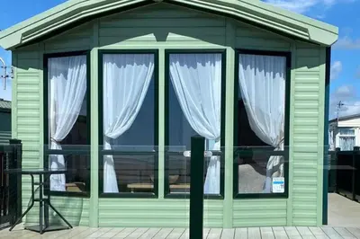 a small green building with white curtains in it at Beachside Lodge - Sleeps 6 - Pets ok - Parking in Morecambe