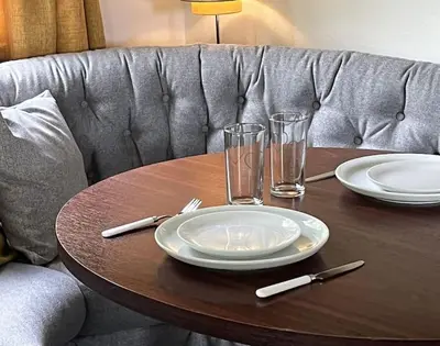 a wooden table with plates and glasses on a couch at Hare Meadow Lodge in Mellor