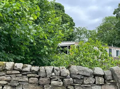 a stone wall in front of a house at Hare Meadow Lodge in Mellor