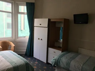a bedroom with a bed and a dresser and a window at Walford Hotel in Blackpool
