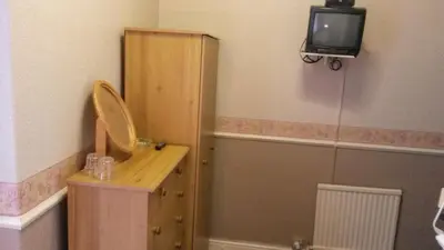 a bathroom with a wooden cabinet and a tv on the wall at Walford Hotel in Blackpool