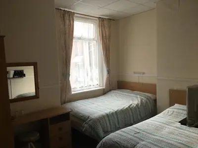a small room with two beds and a window at Walford Hotel in Blackpool