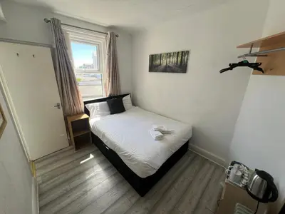 a small bedroom with a bed with white sheets and a window at Henson hotel in Blackpool