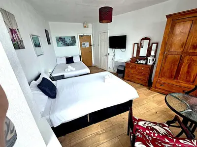 a bedroom with two beds and a table and a television at Henson hotel in Blackpool