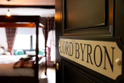 a sign on a door of a bedroom with a bed at The Kings Arms in Cartmel