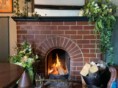 a brick fireplace with two pots in front of it at The Kings Arms in Cartmel