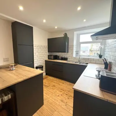 a large kitchen with black cabinets and a wooden floor at MOREaccom Maisonette in Morecambe